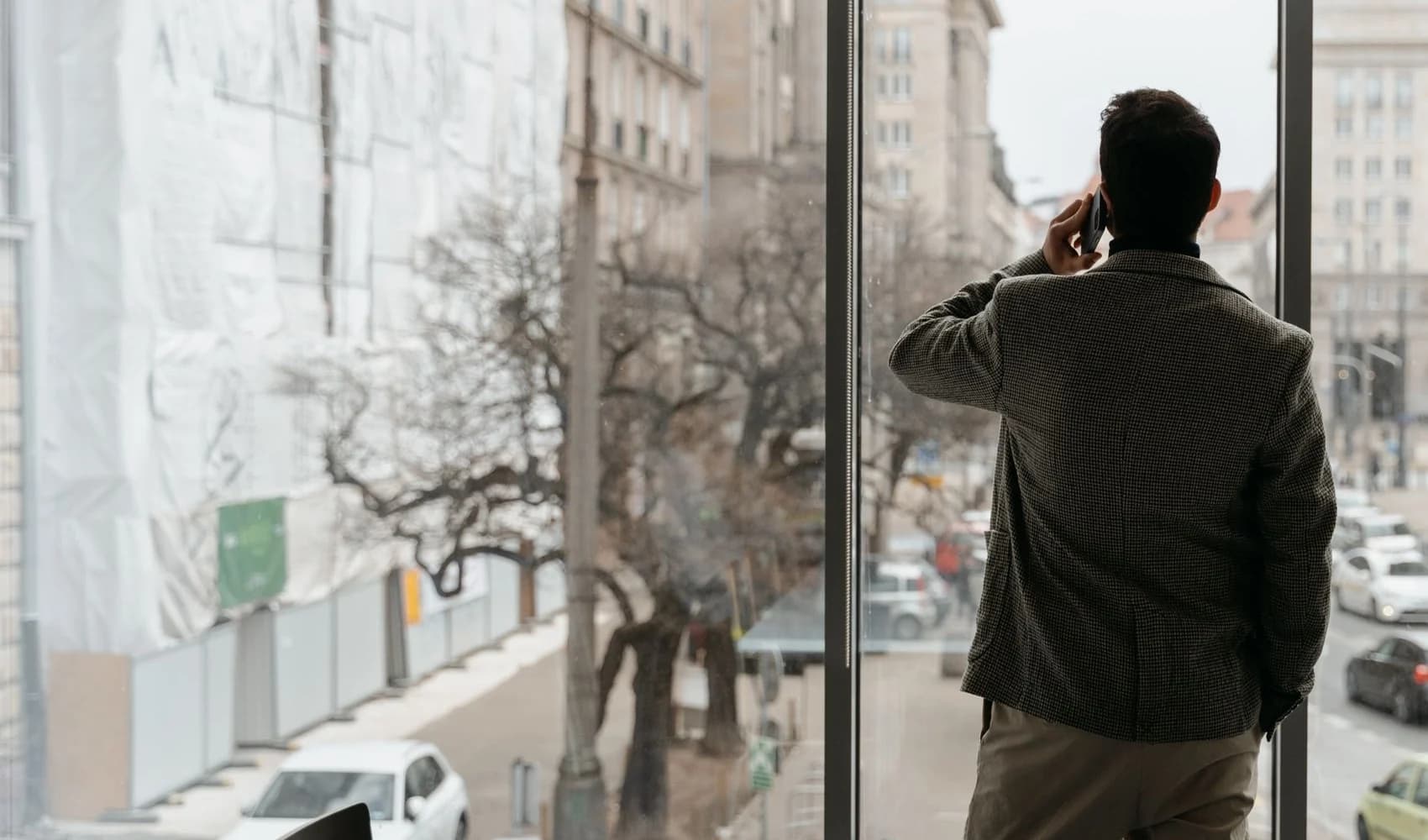 A client stands at a full-height window looking over a city street