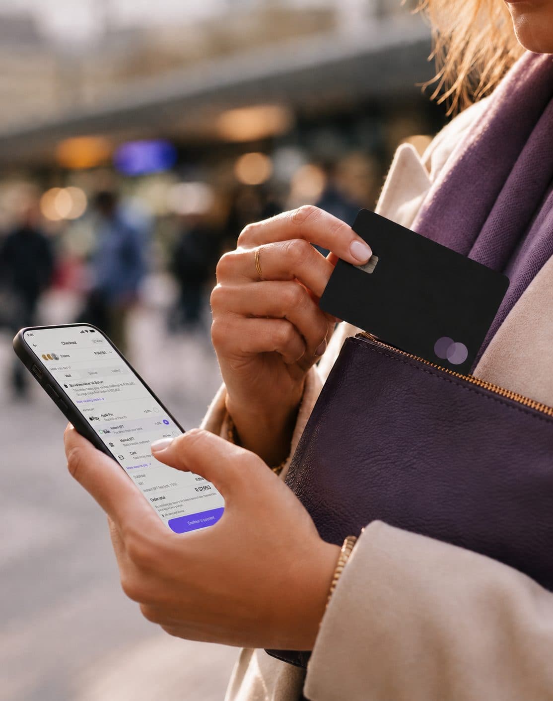 A customer holds her bank card and phone at checkout.
