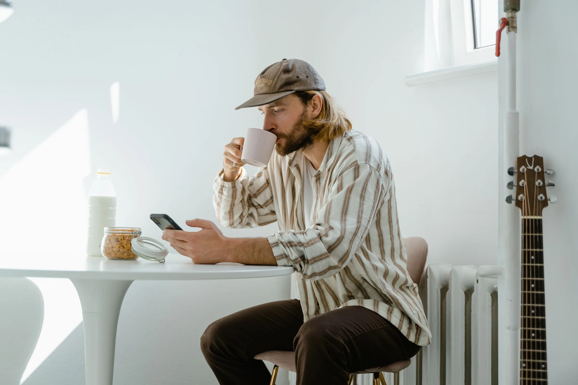 A man enjoying a quiet moment with a coffee at a sunlit table.