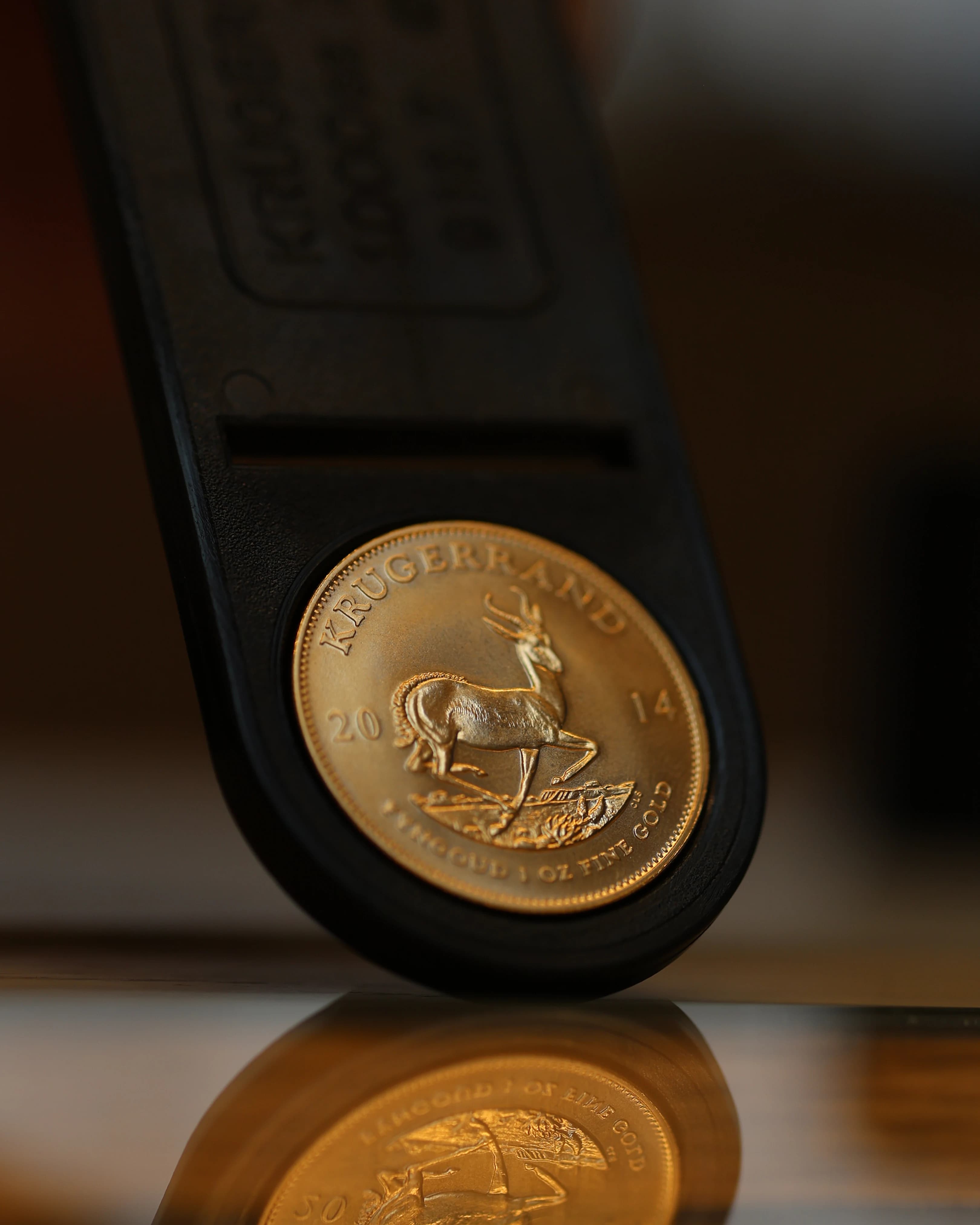 Gold Krugerrand displayed in an open presentation case, reflected on the surface below.